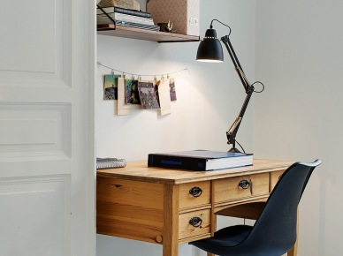 Drewniane biurko z szufladami,czarne krzesło na metalowych nogach,czarna lampka biurkowa i drewniane półki w domowym biurze (25869)