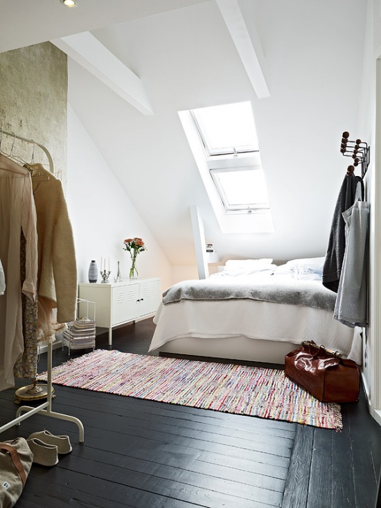 Skandynawska sypialnia na poddaszu z betonową ścianą i białymi belkami