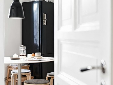 Drewniane stołki i czarna lodówka z lampą w kuchni (20819)
