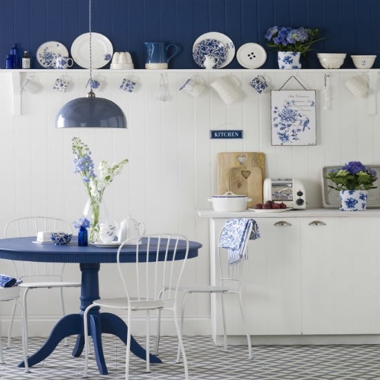 Okragły stół niebieski,niebieskie ściany i białe lamperie w nowoczesnej wiejskiej  kuchni