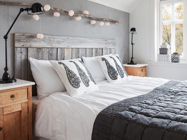 Światełka zawieszone tuż nad drewnianą ramą łóżka są idealną dekoracją i dodają całej sypialni smaku.