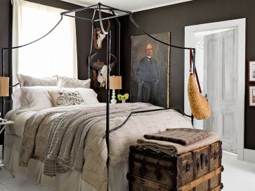 ciemnoszara sypialnia dobrze prezentuje się z białą podłogą i kutym, czarnym łóżkiem. Dekoracje w bieli i drewniany...