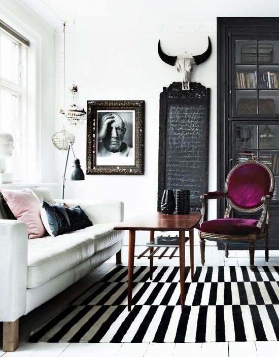 Biało-czarny dywan skandynawski w paski,stylowe krzesło francuskie w śliwkowej tapicerce,czarna tablica w stylowej ramie,czarna witryma,drewniany stolik z lat 60-tych,fotografia portret w retro ramach