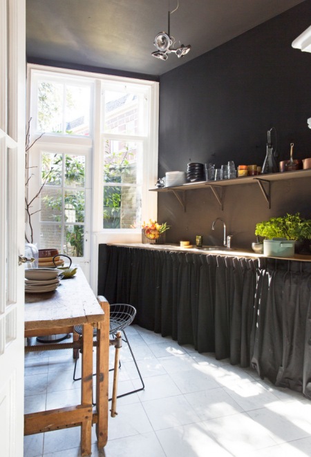 Czarna ściana w kuchnii z rustykalnymi szafkami z faruchami zamiast drzwiczkami