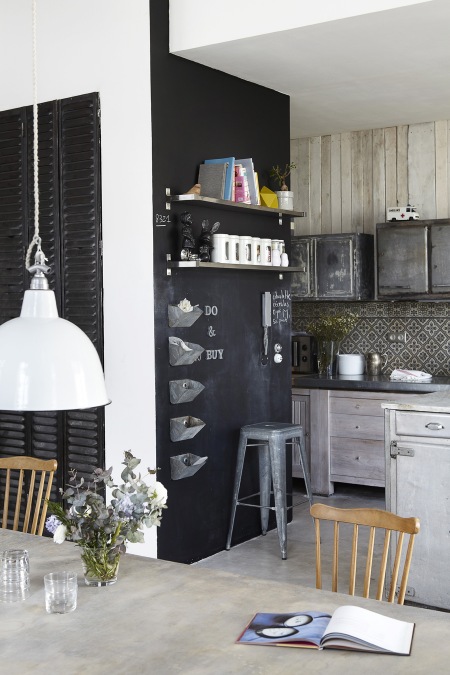 Czarna ściana, szare meble z drewna i metalowe lampy i stołki w kuchni