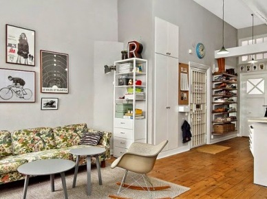 Wiszące półki, gabloty,szare stoliki,krzesła na płozach i zielona wzorzysta sofa w salonie (26380)