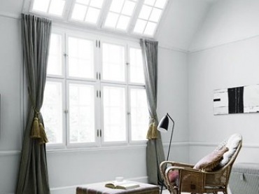 Duże okna z sufitowym swietlikie,mietowe zasłony z chwostami,etniczny puf i wiklinowy fotel w skandynawskim salonie (22060)