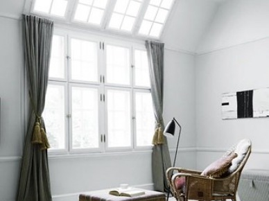 Duże okna z sufitowym swietlikie,mietowe zasłony z chwostami,etniczny puf i wiklinowy fotel w skandynawskim salonie (22060)