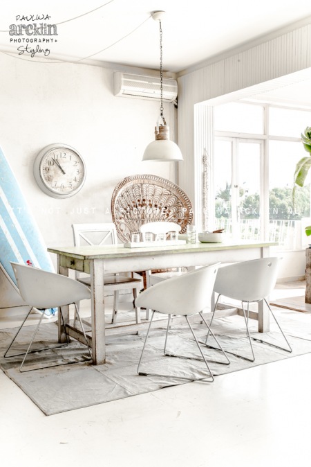 Biała aranżacja jadalni z bielonym stołem w stylu vintage i nowoczesnymi krzesłami na metalowych płozach