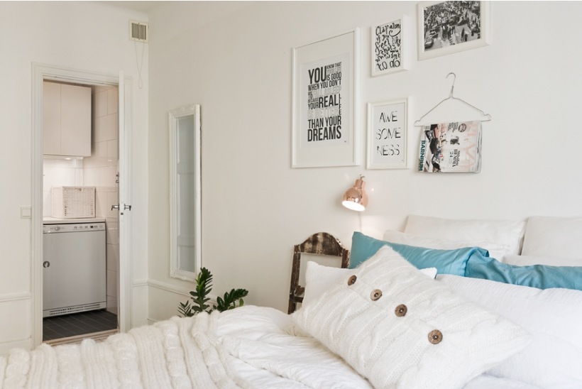 Typografie i grafiki na ścianie w sypialni z białymi i turkusowymi poduszkami