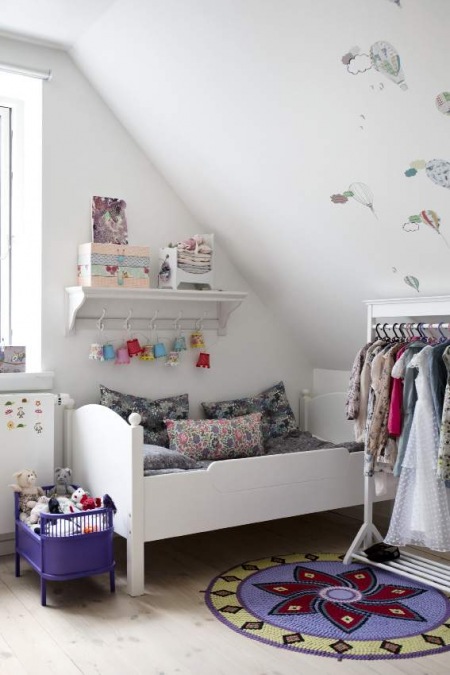 Dziergane dywaniki i drewniane łóżko w dziecięcym pokoju
