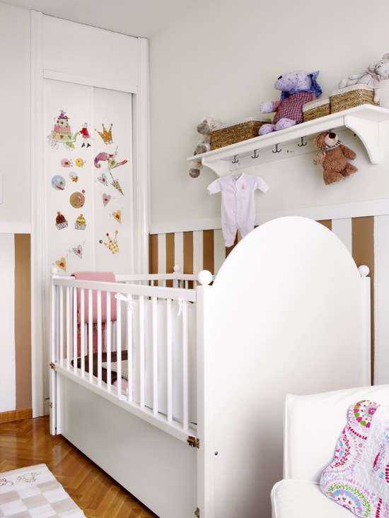 Drewniane białe łóżeczko z półką  i szafa zabudowana w ścianie w dziecięcym pokoju