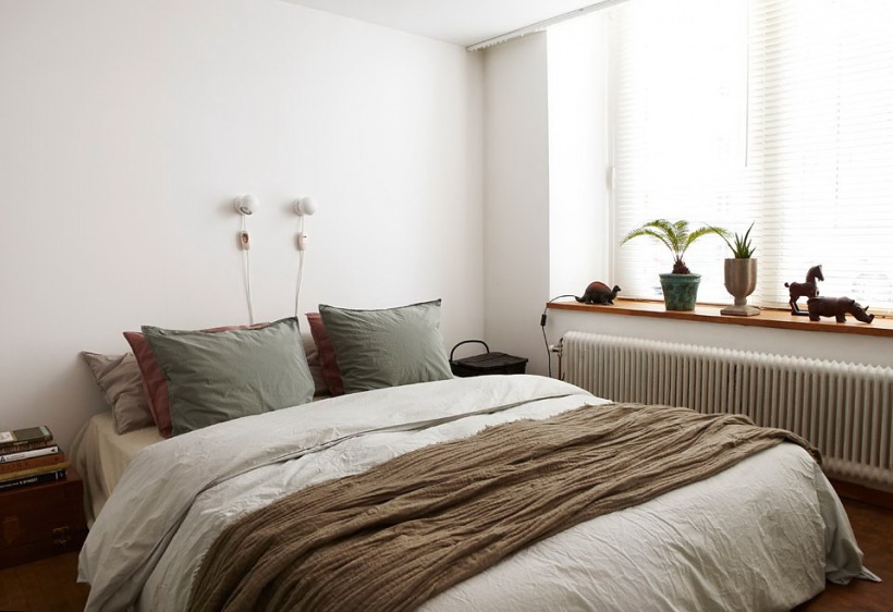 Biała sypialnia z beżową narzutą i szarymi poduszkami