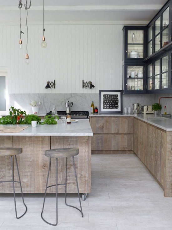 Bielone drewno na frontach kuchennych,czarne wiszące witrynki,żarówki na kablach i industrialne metalowe stołki z drewnianymi blatami w kuchni w industrialnym stylu