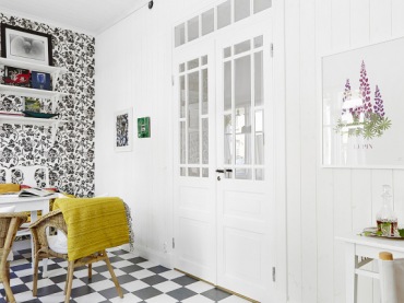Francuskie drzwi dwuskrzydłowe,biale póli na ścianie z biało-czarną tapetą,podłoga w szachownicę i biały stół z wiklinowymi fotelikami (24665)