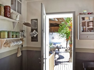 Szare lamperie na ścianach,drewniane szare szafki i białe półki w aranżacji kuchni wychodzącej na taras (24939)