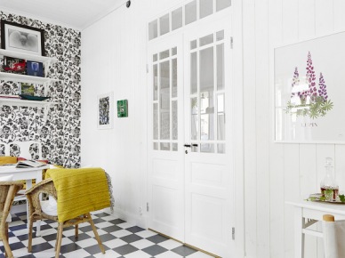 Francuskie drzwi dwuskrzydłowe,biale póli na ścianie z biało-czarną tapetą,podłoga w szachownicę i biały stół z wiklinowymi fotelikami (24665)
