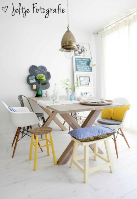 Stół z naturalnego drewna z różnymi krzesłami w w białym, żółtym i szarym kolorze