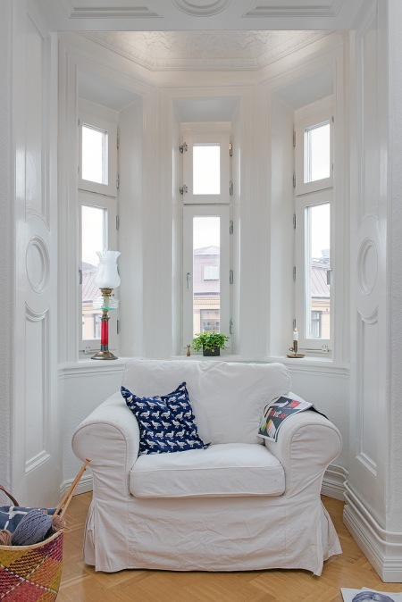 Stylowy wykusz z oknami i białymi sztukateriami i fotelem
