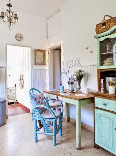Turkusowy stół i kredens z drewnianym blatem,i niebieskim fotelem z rattanu w kuchni vintage