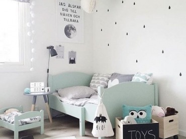 Błękitne łóżeczko w pokoju dziecięcym dodaje cudownego charakteru. Lekki wzór w kropelki na tapecie tworzy bajkową...