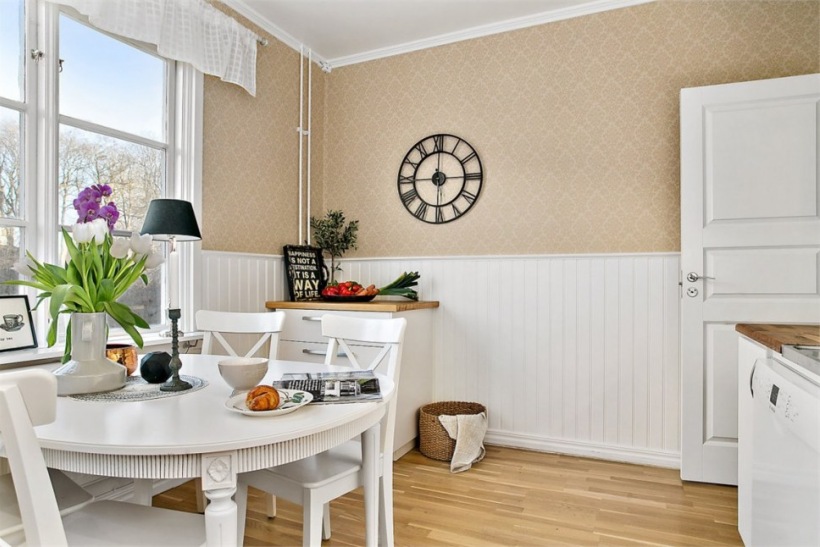 Stylowa beżowa tapeta na ścianie w jadalni,białe drewniane lamperie i biały okrągły stół z krzesłami w stylu skandynawskim