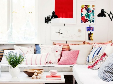 Czerwone, różowe i niebieskie poduszki dekoracyjne na sofie i kolorowe plakaty na ścianie (28056)