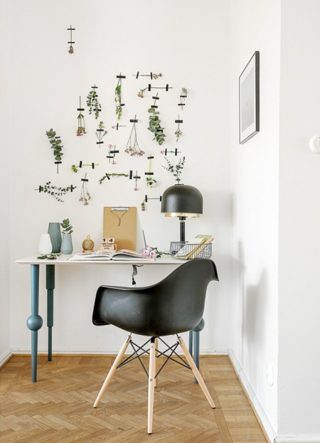 Biały stolik na niebieskich toczonych nogach w roli biurka we wnęce przedpokoju,ziołowe dekoracje na ścianie