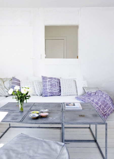 Industrialny stolik kawowy z metalu i biało-fioletowe poduszki na sofie w salonie