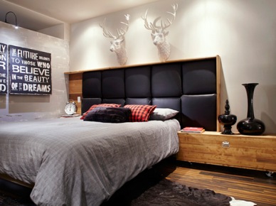 Nowoczesne drewniane łóżko z czarnym pikowanym zagłówkiem, typografie i białe głowy jelonków w męskiej sypialni (24480)