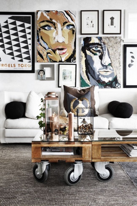 Stolik z palety na kólkach,nowoczesna biała sofa i skandynawskie ilustracje i grafiki na ścianie