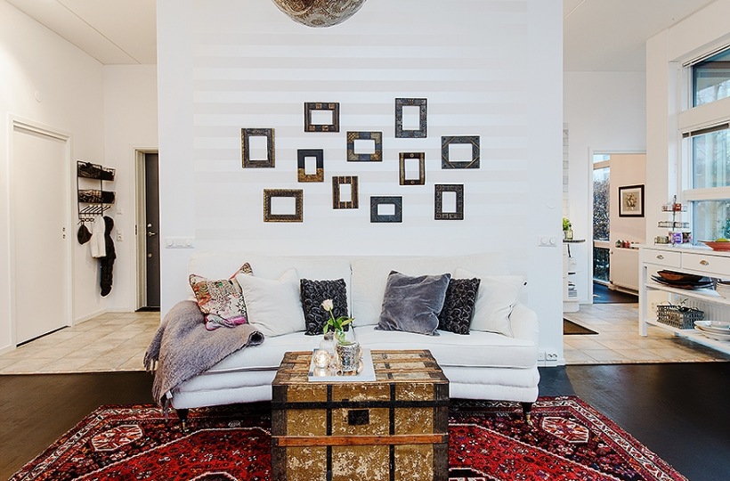 Drewniany kufer i perski dywan w białym salonie z czarną podłogą