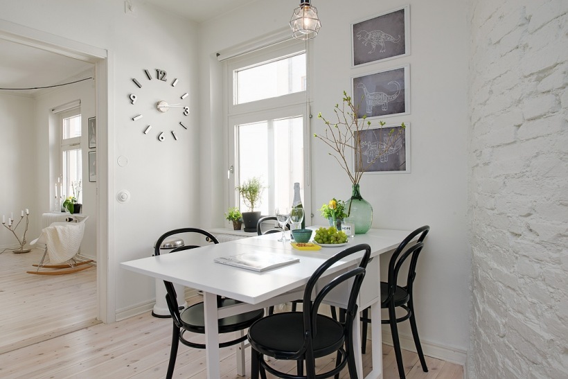 Ceglana ściana pomalowana na biało w jadalni z rozkładanym stołem i czarnymi krzesłami