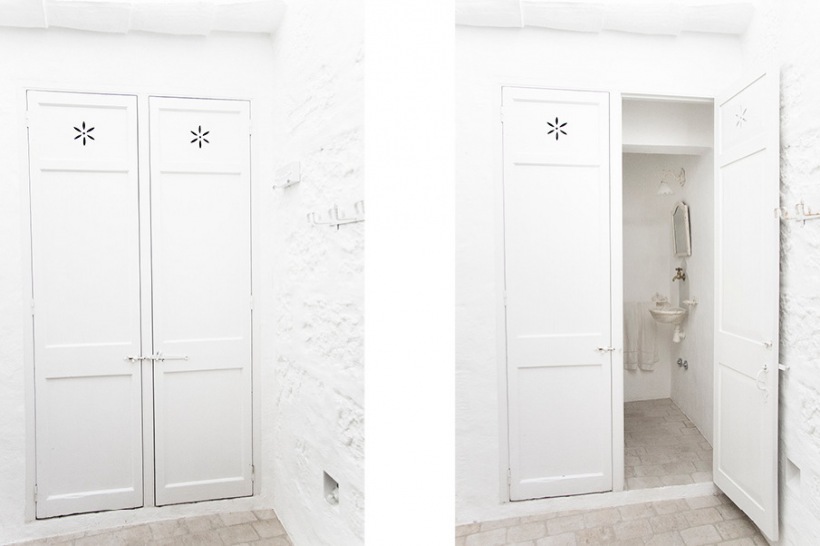 Biała łazienka ukryta we wnęce za podwójnymi drzwiami