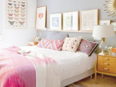 Wystrój sypialni urozmaicają różowe dodatki oraz galeria ścienna na półce nad łóżkiem. Drewniana szafka nocna ociepla...