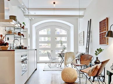 Lekka aranżacja otwartej przestrzeni małego mieszkania w bieli i brązach z metalowymi fotelami z wyplatanymi siedziskami (28086)