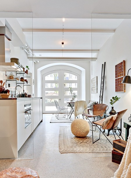 Lekka aranżacja otwartej przestrzeni małego mieszkania w bieli i brązach z metalowymi fotelami z wyplatanymi siedziskami