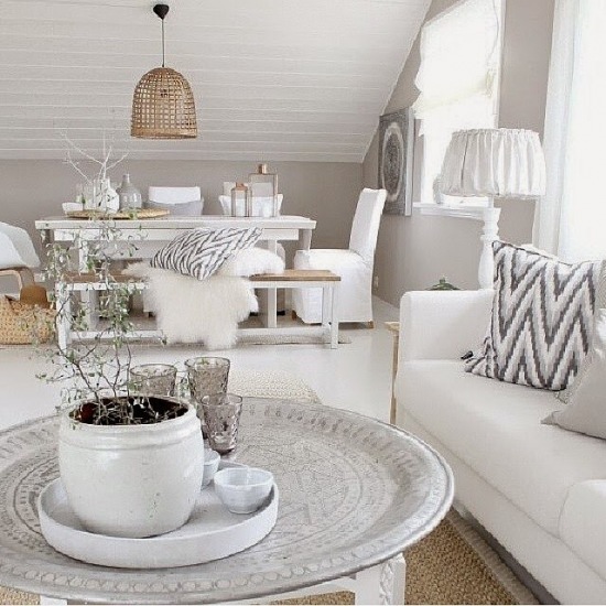 Marokańska taca stolik w otwartym salonie z jadalnią ,biały stół z drewniana ławką,białe ubranka na krzeslach ,białe owcze futrzaki i poduszki w zygzaki