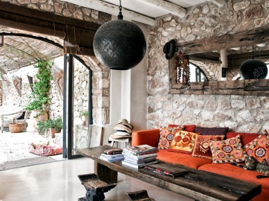 Kamienne ściany,drewniane lustro rustykalne,czarna lampa marokańska i czerwona kanapa z orientalnymi poduszkami (25389)
