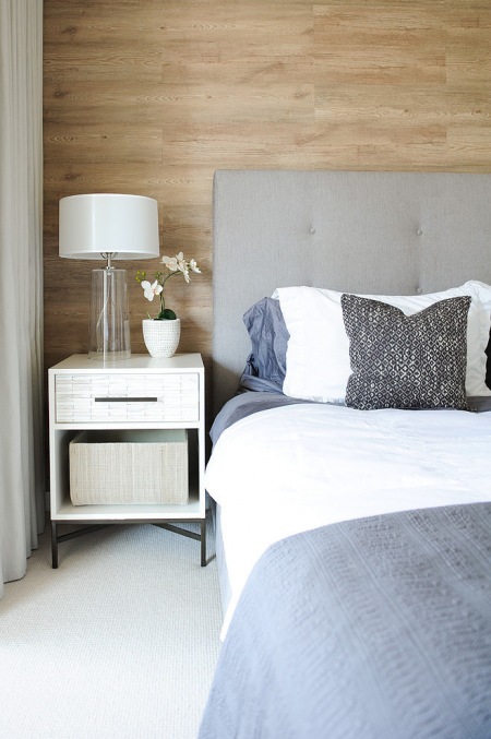 Drewniana okładzina na ścianie, biała podłoga i szare tapicerowane łóżko