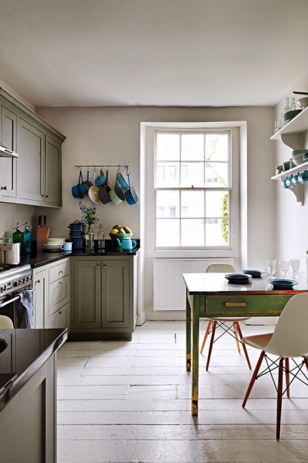 Szara kuchnia z zielonym stołem vintage,białymi krzeslami vitra i niebieskimi akcesoriami kuchennymi