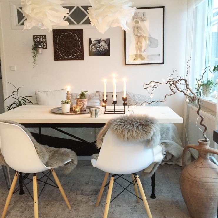Biały stół z białym krzesłami w skandynawskim stylu otoczono wieloma dekoracjami. Warto zwrócić uwagę na galerię...