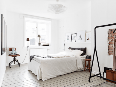 Biała sypialnia z deskami na podłodze, metalowym wieszakiem i brązowymi detalami (21952)