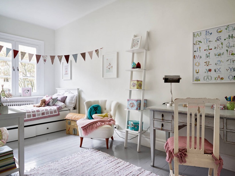 Girlanda z kolorowych proporczyków w pokoju dziecięcym , łóżko z szufladami,biała konsolka i pikowany fotelik,dekoracyjna drabina z pojemnikami i francuskie biurko z krzesłem