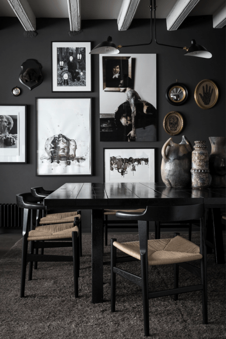 Jadalnia w czerni z galerią biało-czarnych grafik i fotografii, nowoczesną lampą i stylowymi ramkami