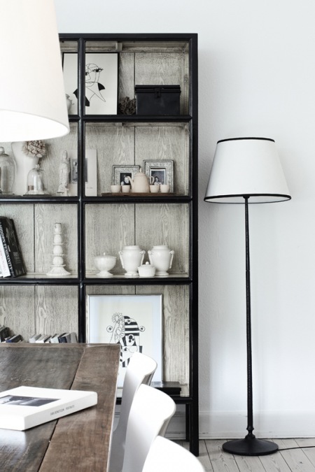 Czarna etażerka ze szklaną witryną i biało-czarne lampy w salonie