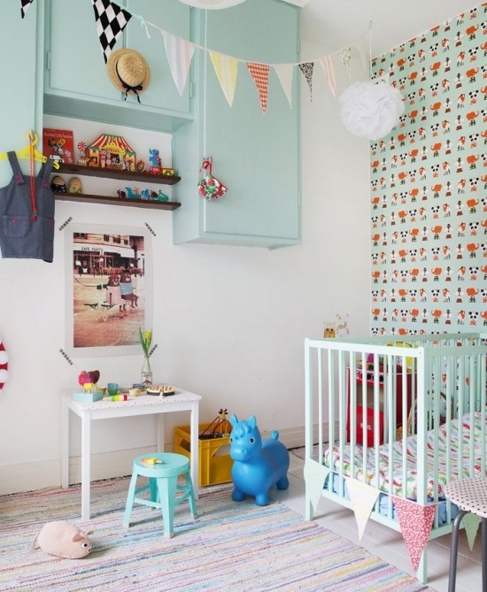 Wzorzysta tapeta na ścianie w pokoju dla dziecka,mietowe drewniane mebelki dziecięce,proporczyki i pompony dekoracyjne