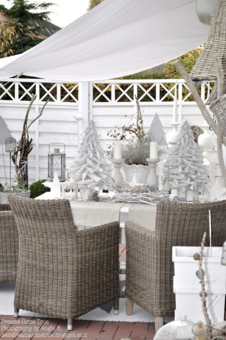 Śnieżnobiałe dekoracje świąteczne w aranżacji białego tarasu z rattanowymi fotelami