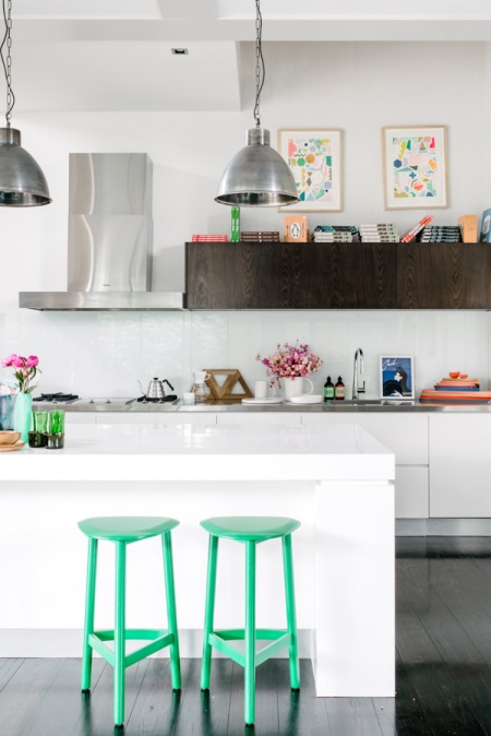 Turkusowe neonowe stołki pzy białej wyspie w nowoczesnej kuchni