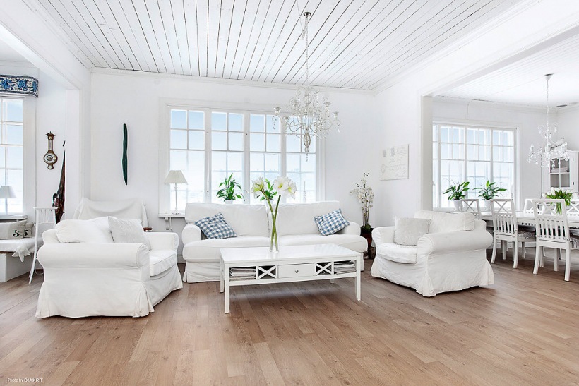 Białe sofy i fotele z drewnianym, skandynawskim stolikiem do kawy